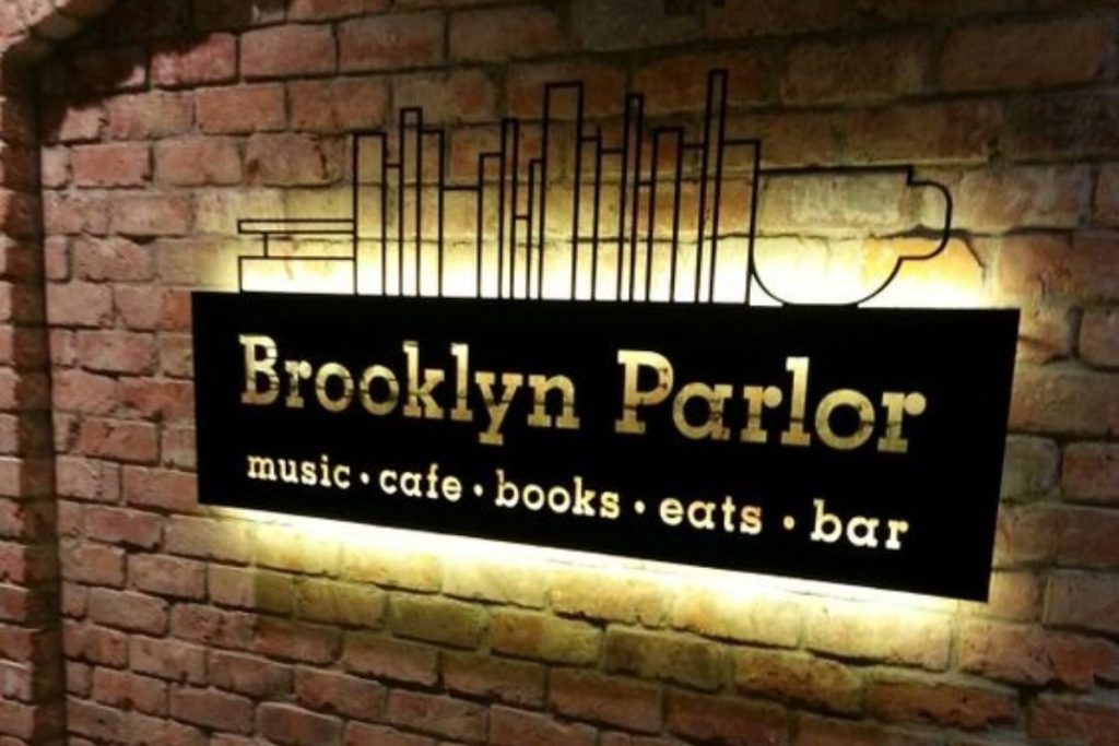 Biển hiệu Brooklyn Parlor chữ nổi hắt sáng trên tường gạch